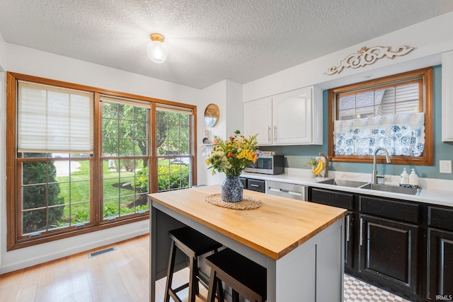 15025 Water Oak Pl, Huntertown, IN 46748 - kitchen featuring a sink, butcher block countertops, white cabinetry, stainless steel microwave, and a textured ceiling