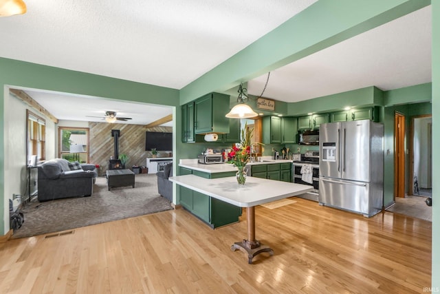 2395 State Road 427th Hwy, Waterloo, IN 46793 - kitchen featuring green cabinets, appliances with stainless steel finishes, a wood stove, light countertops, and light wood-type flooring