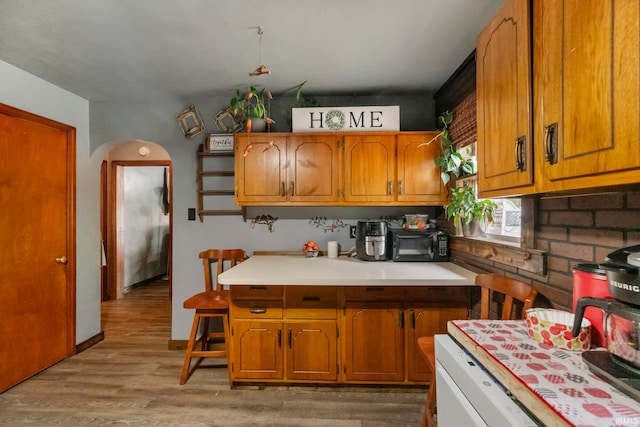 2526 S Airport Rd, Monticello, IN 47960 - kitchen with brown cabinets, arched walkways, light wood finished floors, and light countertops