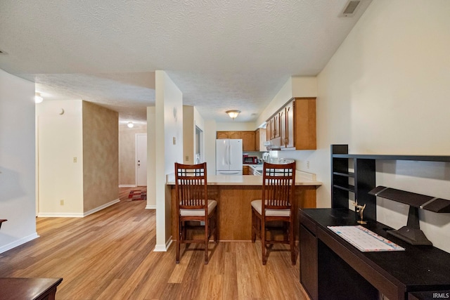 511 Westview Cir, West Lafayette, IN 47906 - kitchen featuring freestanding refrigerator, brown cabinets, light wood-type flooring, a textured ceiling, and light countertops
