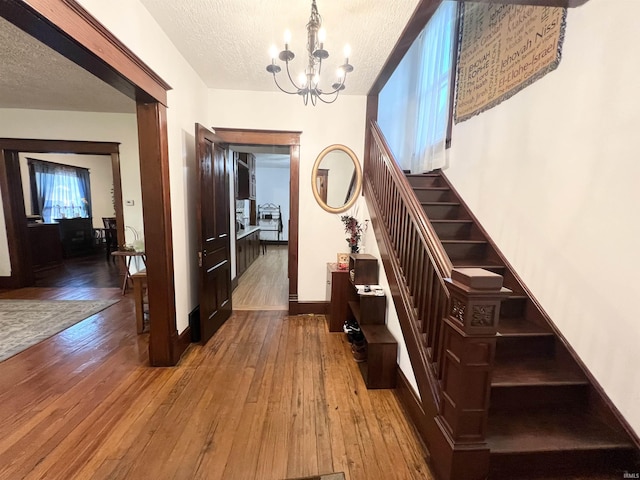 400 Burlington Ave, Logansport, IN 46947 - foyer entrance featuring stairs, a chandelier, a textured ceiling, hardwood / wood-style flooring, and baseboards