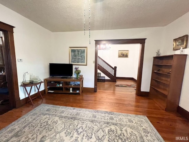 400 Burlington Ave, Logansport, IN 46947 - living area featuring wood finished floors, a textured ceiling, baseboards, and stairs