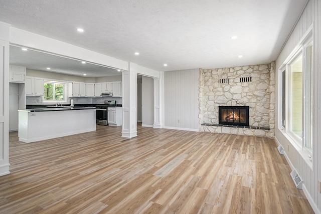 4624 3b Rd, Bremen, IN 46506 - unfurnished living room featuring light wood-style flooring, a fireplace, recessed lighting, a sink, and baseboards