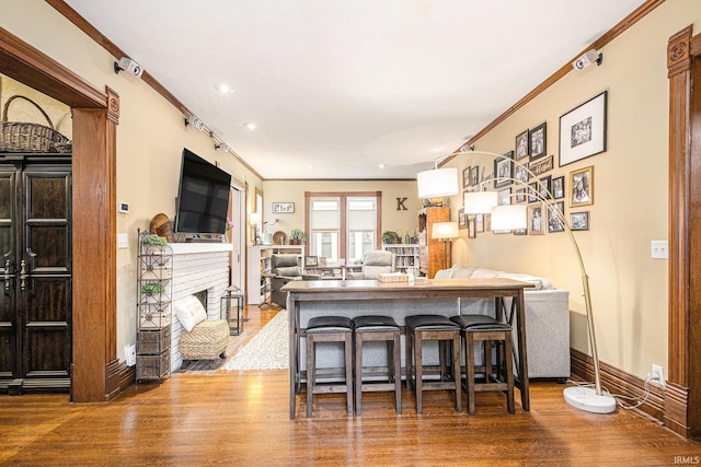 411 S 6th St, Goshen, IN 46526 - kitchen featuring wood finished floors, crown molding, a kitchen bar, a fireplace, and recessed lighting