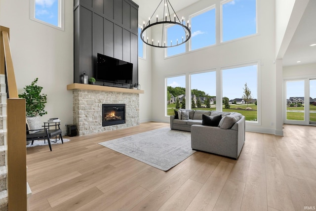 121 Jadis Ct, Fort Wayne, IN 46845 - living area with a towering ceiling, a stone fireplace, light wood-style flooring, a chandelier, and baseboards