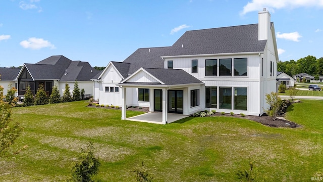 121 Jadis Ct, Fort Wayne, IN 46845 - rear view of property featuring a chimney, a patio area, a yard, board and batten siding, and a shingled roof