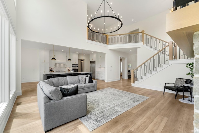 121 Jadis Ct, Fort Wayne, IN 46845 - living room with a high ceiling, stairs, a chandelier, light wood-type flooring, and baseboards
