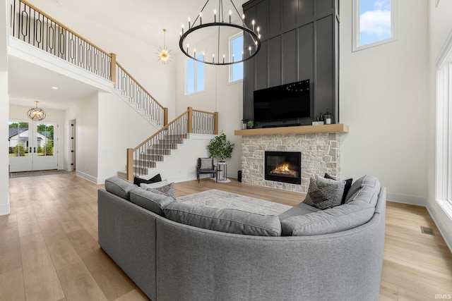 121 Jadis Ct, Fort Wayne, IN 46845 - living room with a chandelier, a high ceiling, light wood-type flooring, a stone fireplace, and baseboards