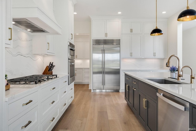 121 Jadis Ct, Fort Wayne, IN 46845 - kitchen with appliances with stainless steel finishes, a sink, custom exhaust hood, white cabinetry, and decorative light fixtures