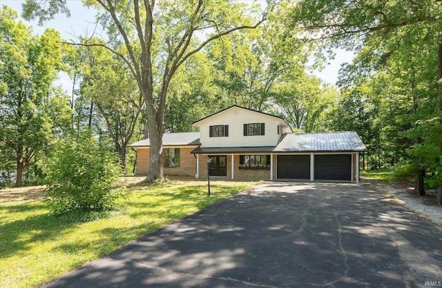 633 S Ravencrest Ave, Bloomington, IN 47401 - view of front of property featuring a garage, driveway, metal roof, a front yard, and covered porch