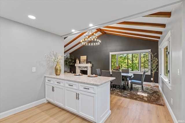 633 S Ravencrest Ave, Bloomington, IN 47401 - kitchen with a peninsula, light wood finished floors, a chandelier, white cabinets, and baseboards