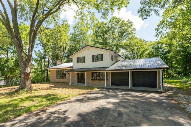 633 S Ravencrest Ave, Bloomington, IN 47401 - tri-level home with a garage, asphalt driveway, metal roof, a chimney, and covered porch