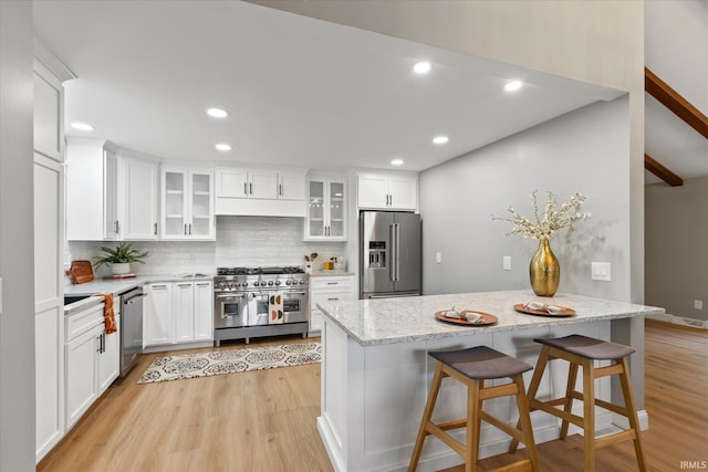 633 S Ravencrest Ave, Bloomington, IN 47401 - kitchen featuring premium appliances, light wood-type flooring, backsplash, white cabinetry, and recessed lighting