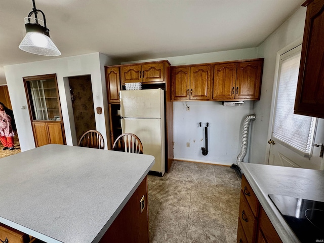 2940 19th St, Columbus, IN 47201 - kitchen featuring freestanding refrigerator, black electric stovetop, hanging light fixtures, brown cabinetry, and light countertops