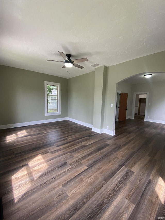 1824 Boxcar Ln, Auburn, IN 47606 - empty room with arched walkways, dark wood-style floors, a ceiling fan, and baseboards