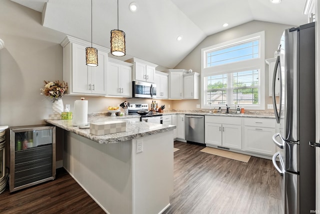 17009 Hamptons Pkwy, New Haven, IN 46774 - kitchen featuring stainless steel appliances, a peninsula, white cabinets, decorative light fixtures, and dark wood-style flooring