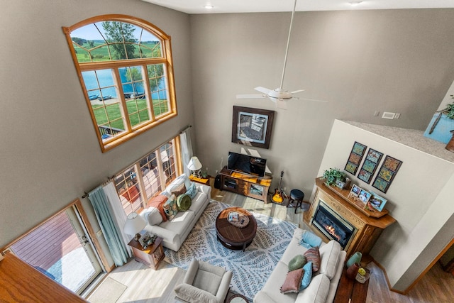 6378 N 100 E, Ossian, IN 46777 - living room with wood finished floors, a towering ceiling, a glass covered fireplace, a ceiling fan, and baseboards