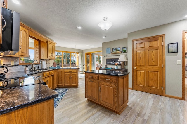 6378 N 100 E, Ossian, IN 46777 - kitchen with light wood-style floors, brown cabinetry, a textured ceiling, a peninsula, and a kitchen island