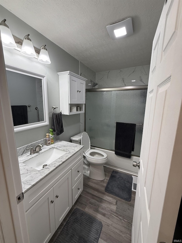 2520 Foxhall Dr, Lafayette, IN 47909 - full bathroom with a textured ceiling, vanity, wood finished floors, combined bath / shower with glass door, and toilet