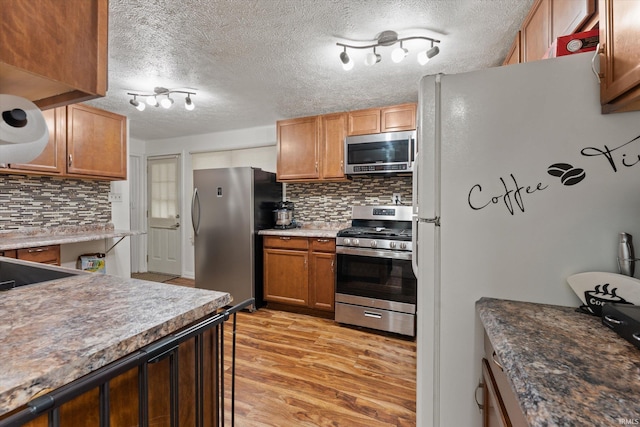 2614 N Main St, Mishawaka, IN 46545 - kitchen with appliances with stainless steel finishes, decorative backsplash, light wood-style floors, a textured ceiling, and a breakfast bar area