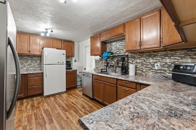 2614 N Main St, Mishawaka, IN 46545 - kitchen featuring stainless steel appliances, a sink, wood finished floors, tasteful backsplash, and brown cabinets
