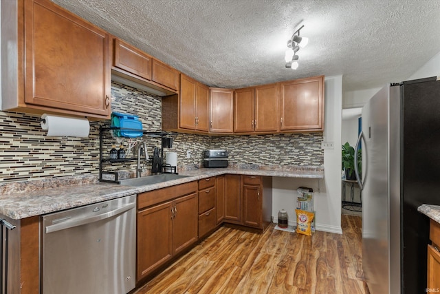 2614 N Main St, Mishawaka, IN 46545 - kitchen with stainless steel appliances, a sink, light wood-style flooring, brown cabinets, and a textured ceiling
