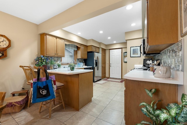 1114 Packard Pl, Auburn, IN 46706 - kitchen with stainless steel fridge, backsplash, a peninsula, light countertops, and a breakfast bar