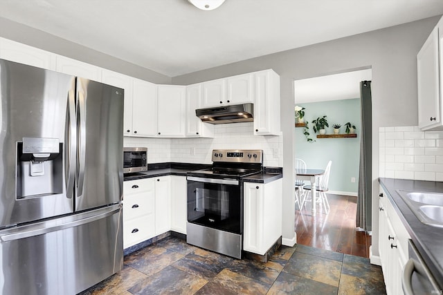 843 S Lantern Ln, Ellettsville, IN 47401 - kitchen featuring stainless steel appliances, under cabinet range hood, dark countertops, decorative backsplash, and white cabinetry