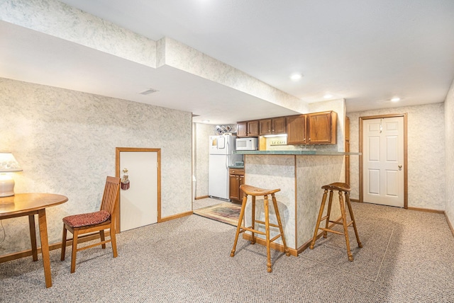 58078 Windsong Dr, Elkhart, IN 46517 - kitchen featuring white appliances, light carpet, a kitchen bar, brown cabinets, and baseboards