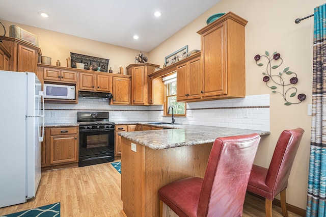 58078 Windsong Dr, Elkhart, IN 46517 - kitchen with white appliances, a sink, under cabinet range hood, a peninsula, and light wood-style flooring