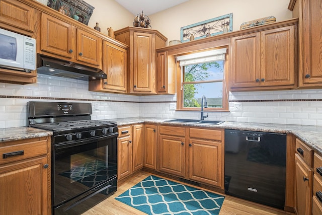 58078 Windsong Dr, Elkhart, IN 46517 - kitchen featuring black appliances, a sink, under cabinet range hood, light wood-type flooring, and backsplash