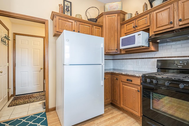 58078 Windsong Dr, Elkhart, IN 46517 - kitchen with white appliances, backsplash, under cabinet range hood, brown cabinetry, and light stone counters