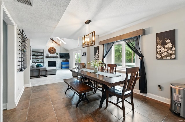 2906 Easton Ridge Pl, Fort Wayne, IN 46818 - dining area with dark tile patterned flooring, a textured ceiling, a fireplace, a chandelier, and vaulted ceiling