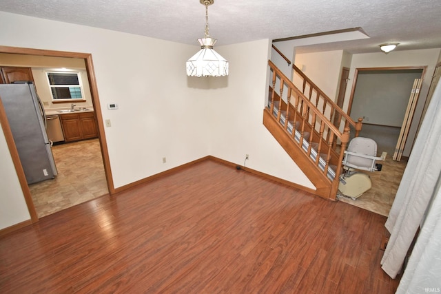 904 Brookridge Ct, Lafayette, IN 47909 - unfurnished room featuring a textured ceiling, light wood-style flooring, stairs, baseboards, and a sink