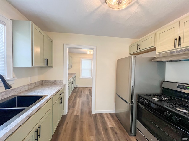 158 Simpson Ave, Elkhart, IN 46516 - kitchen with stainless steel gas range oven, under cabinet range hood, a sink, dark wood-style floors, and light countertops