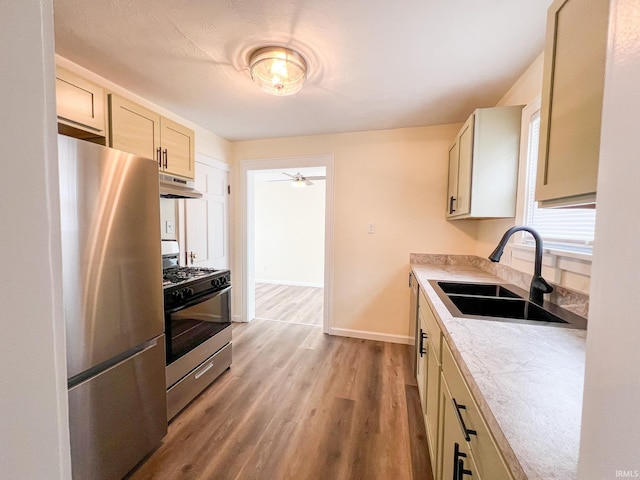 158 Simpson Ave, Elkhart, IN 46516 - kitchen with stainless steel appliances, under cabinet range hood, a sink, light countertops, and wood finished floors