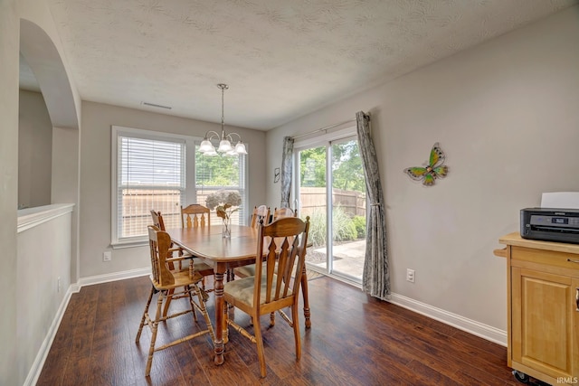4774 W Hidden Meadow Dr, Bloomington, IN 47404 - dining space featuring baseboards, dark wood finished floors, a chandelier, arched walkways, and a textured ceiling