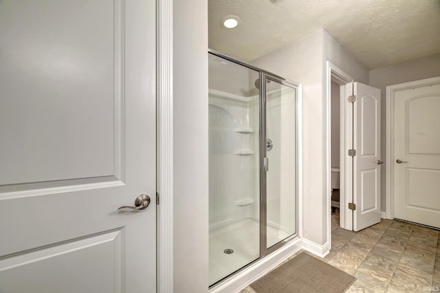 4774 W Hidden Meadow Dr, Bloomington, IN 47404 - bathroom featuring a shower stall, toilet, baseboards, and a textured ceiling