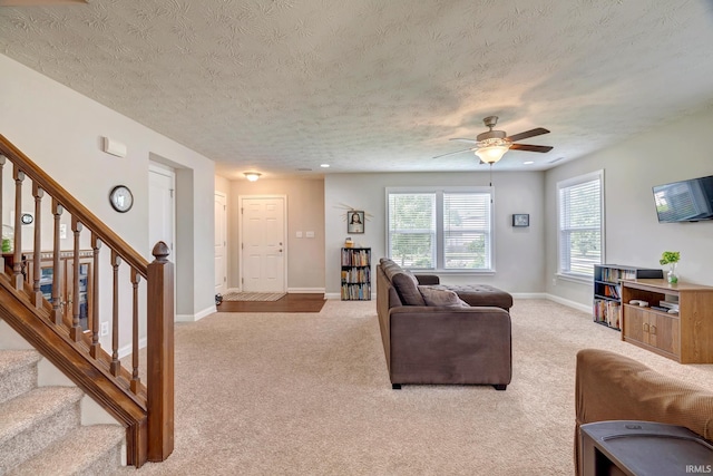 4774 W Hidden Meadow Dr, Bloomington, IN 47404 - living room with stairway, a textured ceiling, a ceiling fan, and light carpet