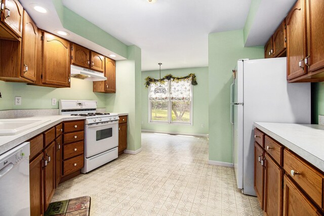18086 Courtland Dr, South Bend, IN 46637 - kitchen with white appliances, under cabinet range hood, light countertops, brown cabinetry, and recessed lighting