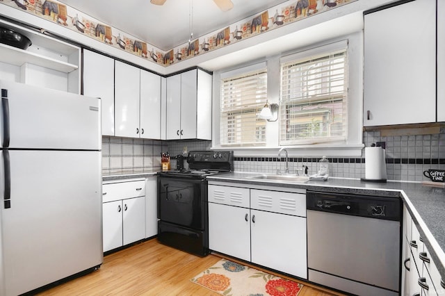 706 Park Ave, South Bend, IN 46616 - kitchen with freestanding refrigerator, dishwasher, black range with electric cooktop, a sink, and white cabinetry