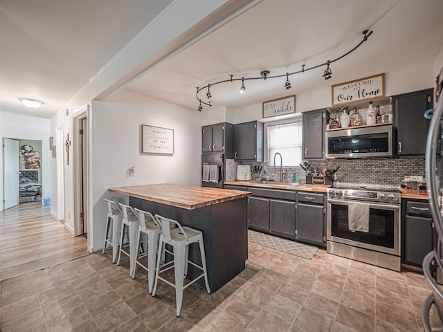 11219 Denzer Rd, Evansville, IN 47712 - kitchen featuring appliances with stainless steel finishes, a sink, butcher block counters, a breakfast bar area, and backsplash