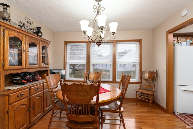 300 S Heritage Dr, Delphi, IN 46923 - dining space with a chandelier, light wood-style flooring, a textured ceiling, and baseboards