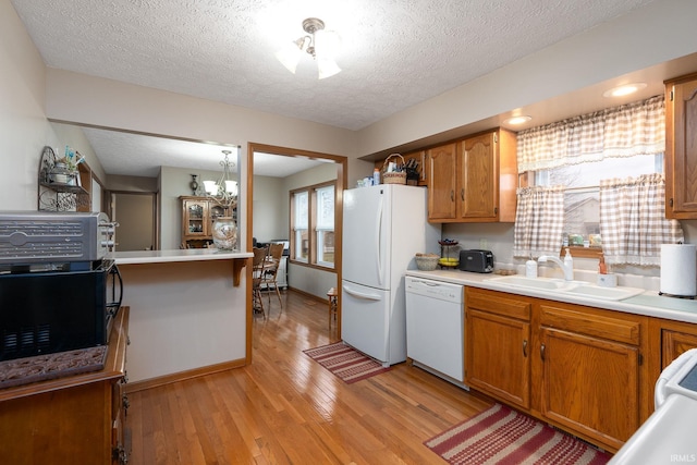 300 S Heritage Dr, Delphi, IN 46923 - kitchen featuring white appliances, a sink, light wood finished floors, a textured ceiling, and brown cabinetry
