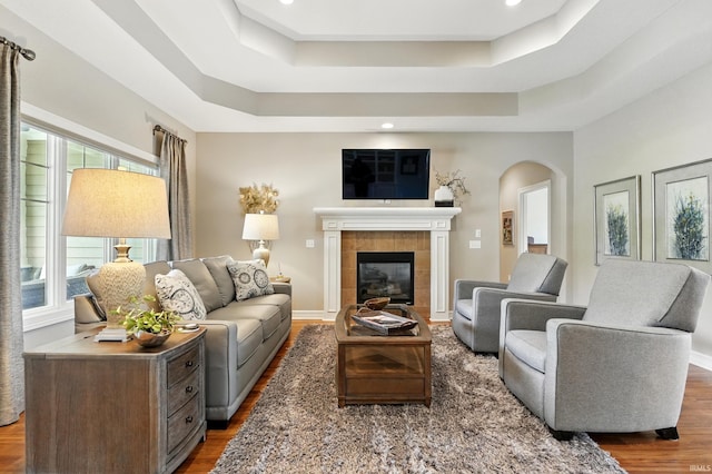 12815 Chaplin Ct, Fort Wayne, IN 46845 - living room featuring a tray ceiling, arched walkways, wood finished floors, a fireplace, and recessed lighting