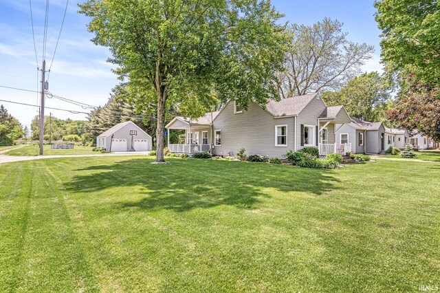 542 E Michigan St, New Carlisle, IN 46552 - view of front of house with a garage, an outbuilding, a front lawn, and covered porch
