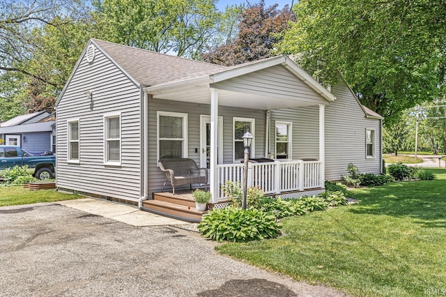 542 E Michigan St, New Carlisle, IN 46552 - bungalow-style home featuring covered porch, roof with shingles, and a front lawn