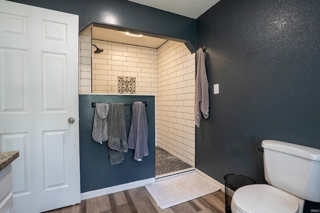 1339 Clark Ave, Bluffton, IN 46714 - bathroom featuring wood finished floors, tiled shower, toilet, and baseboards