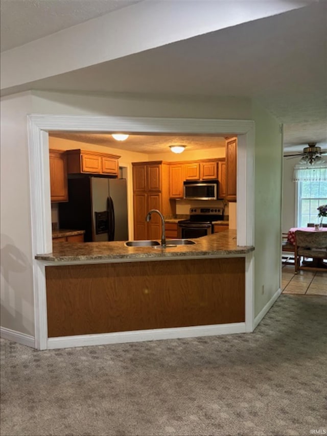 999 Inderrieden Rd, Chandler, IN 47610 - kitchen with stainless steel appliances, a sink, baseboards, brown cabinetry, and carpet flooring