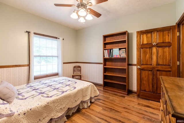 5003 N Chatham Dr, Bloomington, IN 47404 - bedroom with wainscoting, wallpapered walls, wood finished floors, and a ceiling fan